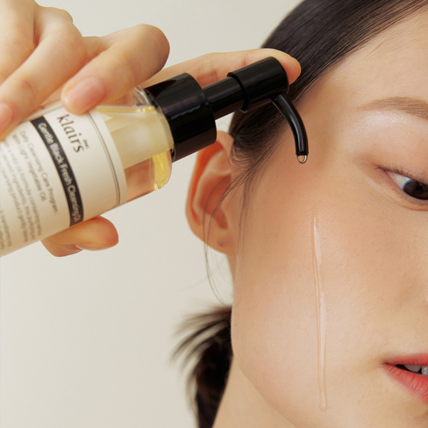 woman applying an oil cleanser (waterless skincare)